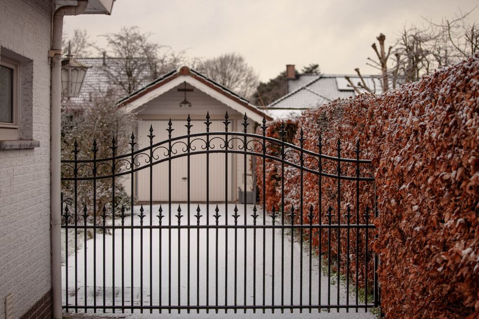 Black metal gate closed across a garden entrance
