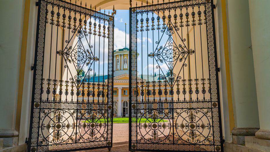 Black metal gate closed across a garden entrance